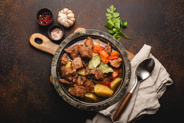 Meat beef stew with vegetables and gravy in rustic metal pot top view