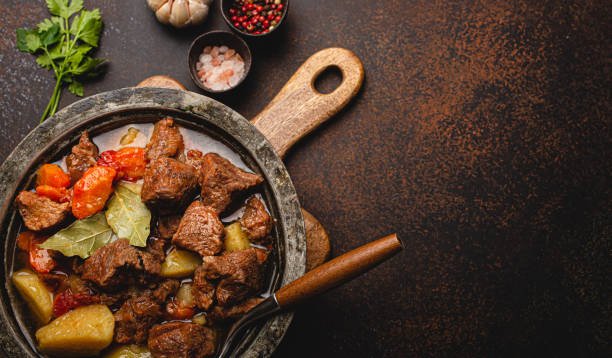 istock Meat beef stew with vegetables and gravy in rustic metal pot top view copy space 1357747140