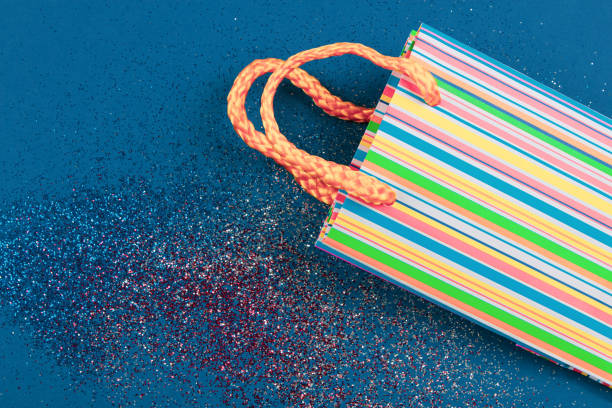 Striped gift bag on abstract red, white and blue glitter sparkle background. Holiday concept. Flat lay. Copy space.