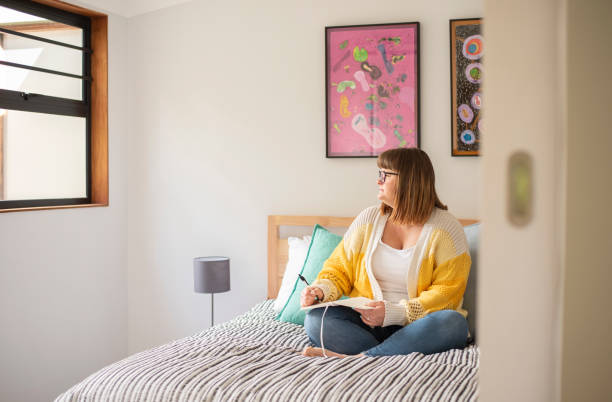 Woman sitting on her bed and writing down her thoughts in a journal stock photo