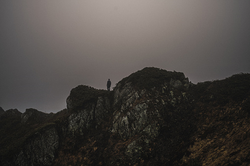 Silhouette of man standing on the top of the mountains at fog and smooth sunlight