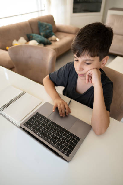 istock Little boys attending to online class in his room. 1357754567