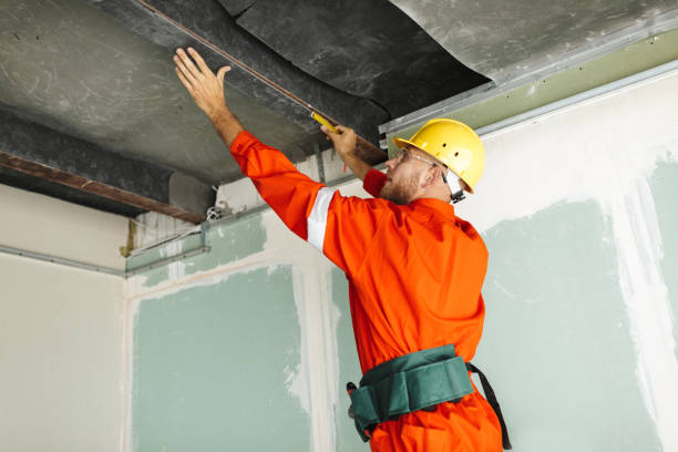 istock Builder in orange work clothes and yellow hardhat using measurin 1357755475