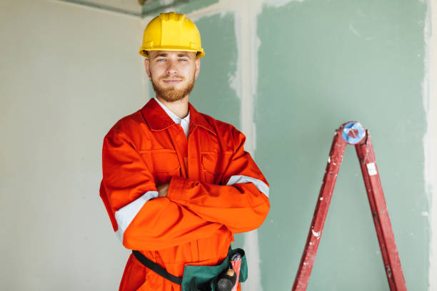 istock Young smiling builder in orange work clothes and hardhat happily 1357755483