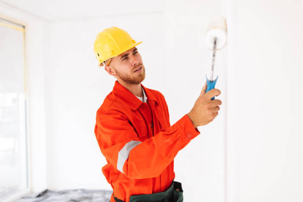 istock Thoughtful foreman in work clothes and yellow hardhat using pain 1357756019