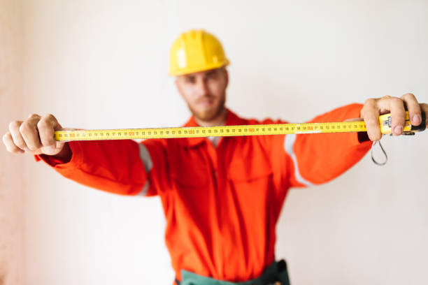 istock Close up foreman in work clothes and yellow hardhat holding meas 1357756023