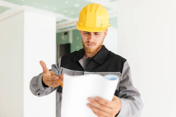 istock Young serious engineer in work clothes and yellow hardhat though 1357757206