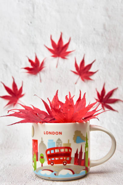 istock Red maple leaves in a mug with flying leaves on background. 1357757363