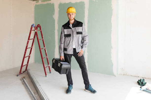 istock Smiling engineer in work clothes and yellow hardhat holding tool 1357757392
