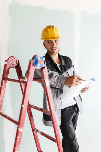 istock Young engineer in work clothes and yellow hardhat dreamily looki 1357757396
