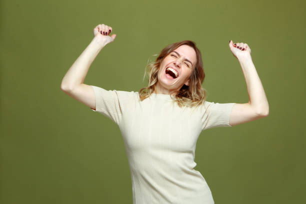 joven exitosa y encantada celebrando la victoria con los brazos levantados, gritando de euforia, felicidad. concepto de fortuna - regocijo fotografías e imágenes de stock