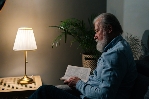 portrait of older man with beard doing reading isolated on black background