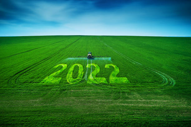 2022 Happy New Year concept and Aerial view of farming tractor plowing and spraying on field. stock photo