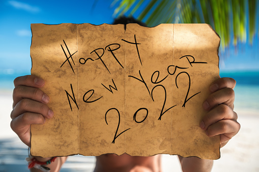 Happy new year 2022 concept with Tourist and vintage map for a treasure on tropical island beach. Punta Cana, Dominican Republic.