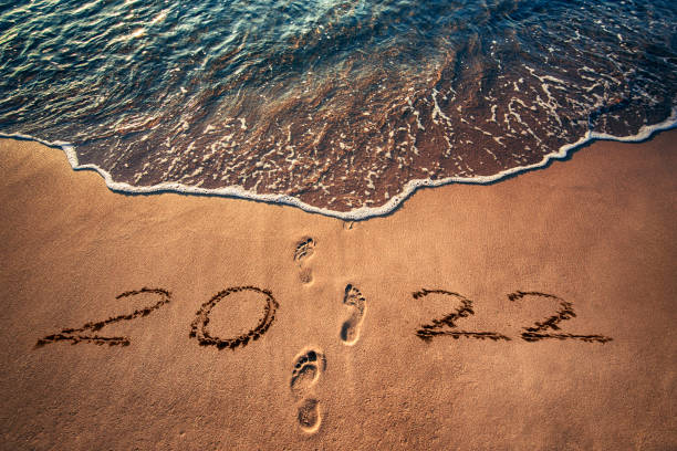 Happy New Year 2022 and ocean sunrise. Foot prints on the sand. Steps on the beach. stock photo