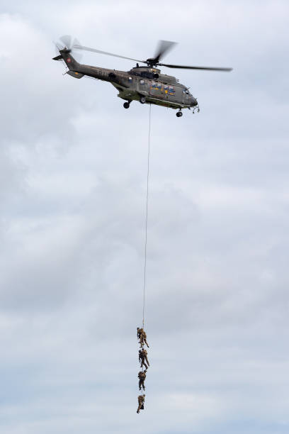 helicóptero utilitario militar aerospatiale as532 de la fuerza aérea suiza que transporta tropas por suspensión de cuerda. - as532 fotografías e imágenes de stock