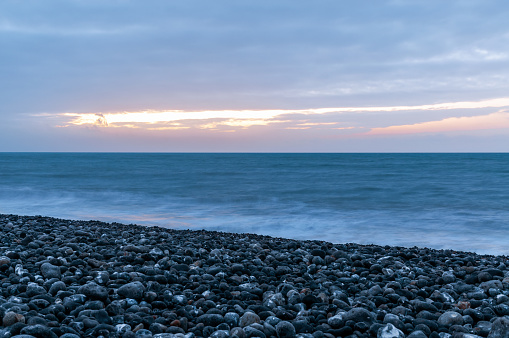 Sunset on the sea, with a pebble beach in Northern France - long exposure