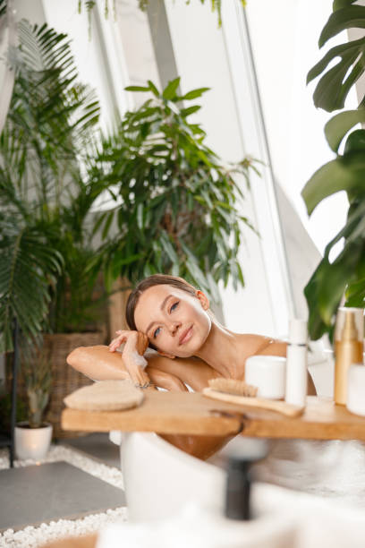 istock Peaceful young woman looking at camera while taking bubble bath at tropical spa resort 1357766574