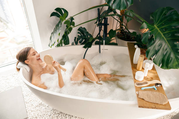 istock Beautiful young woman having fun, singing while relaxing in bathtub at luxury spa resort 1357768902