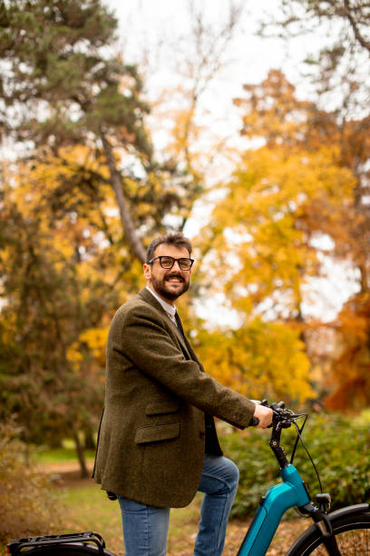 istock Young man with electric bicycle in the autumn park 1357776364