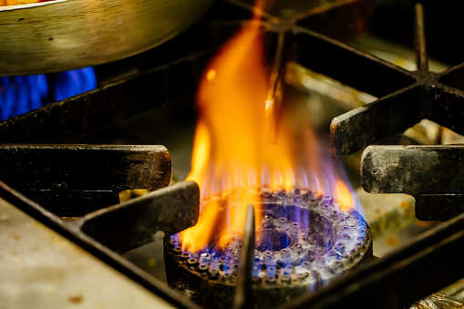 Blue flame from gas stove heating frying pan when cooking food