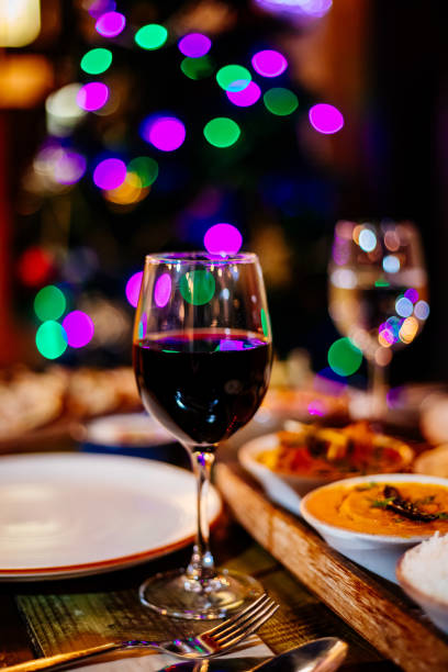 istock Closeup of red wine on table with Christmas table and tree. 1357776523