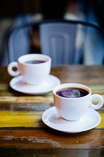 Two cups of black coffee on wooden table