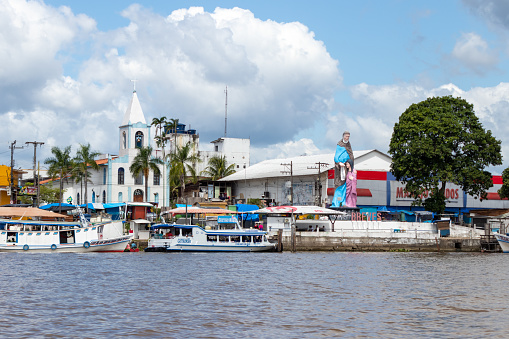 Breves, Para, Brazil - Nov 11, 2021: Riverfront of the city of Breves, overlooking the river port, part of the local shops and the statue and church of Our Lady of Santana.