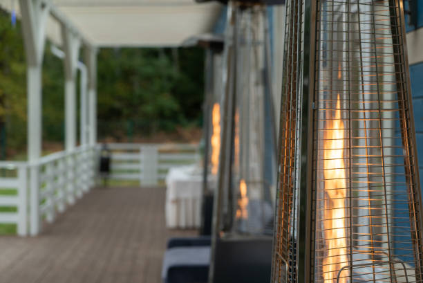 Burning fire in a gas outdoor heater working on terrace. Steel metal pyramid Burning fire in a gas outdoor heater working on terrace. Steel metal pyramid. Warming device propane photos stock pictures, royalty-free photos & images
