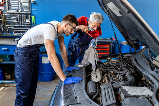 a car maintenance man is checking the motor oil in the car in auto service with a young assistant. - old men car oil imagens e fotografias de stock