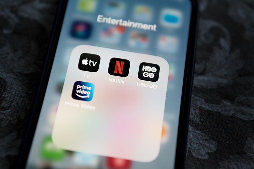 Krakow, Poland - November 28, 2021: Netflix application icon among Apple TV+, Amazon Prime Video, and HBO GO in Entertainment Folder on Apple iPhone 12 Pro MAX screen close-up. Popular streaming services.