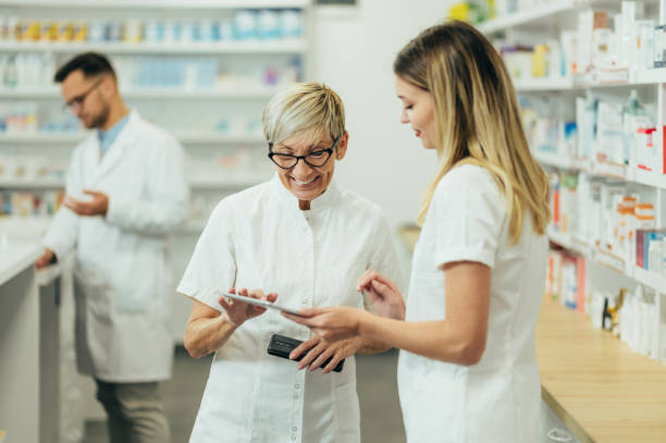 istock Senior female pharmacist using a tablet while working in a pharmacy with her young colleague 1357786307