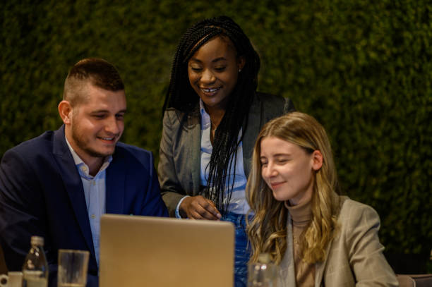 istock Cheerful work colleagues working on a laptop while having a meeting in a cafe 1357786315