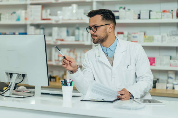 Portrait of a handsome pharmacist working in a pharmacy Portrait of a handsome pharmacist working in a pharmacy and using a computer modafinil online pharmacy stock pictures, royalty-free photos & images