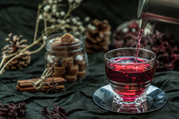 istock Roselle tea (Jamaica sorrel, Rozelle or hibiscus sabdariffa ) is poured from a kettle into glass cup  with dry roselle and brown cane sugar cube. 1357788246