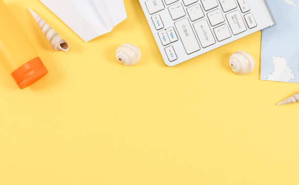 istock Keyboard, world map, seashells, paper plane and sun cream on light yellow 1357797414