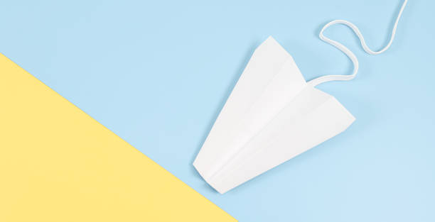 istock White paper plane with a lace trail on the left on a light yellow blue . 1357797422