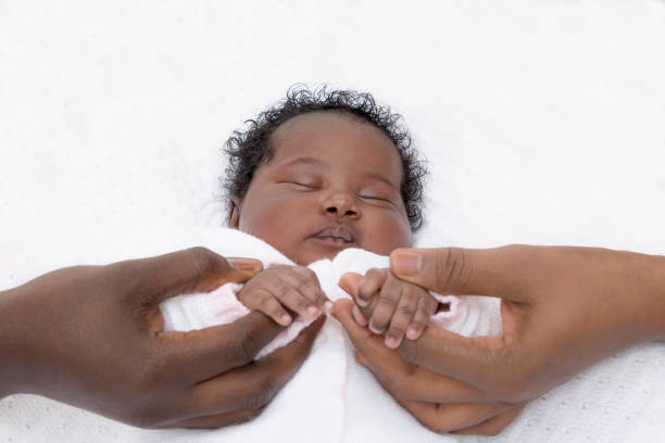 father and mother holding a hand of their one-month-old baby girl while she is sleeping, photo, white background - family american culture african culture black imagens e fotografias de stock
