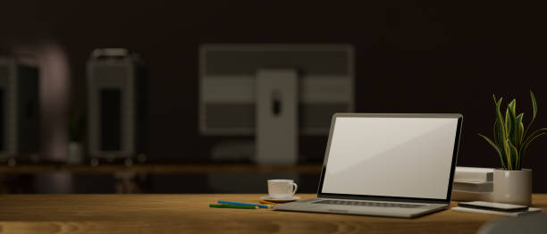 istock Laptop and mockup space on table over dark office in the background. 1357799276