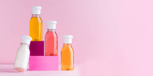 mockup multicolored plastic bottles with shower gel, shampoo for children and adults on a pink background. copy space. - plastic fles klein stockfoto's en -beelden