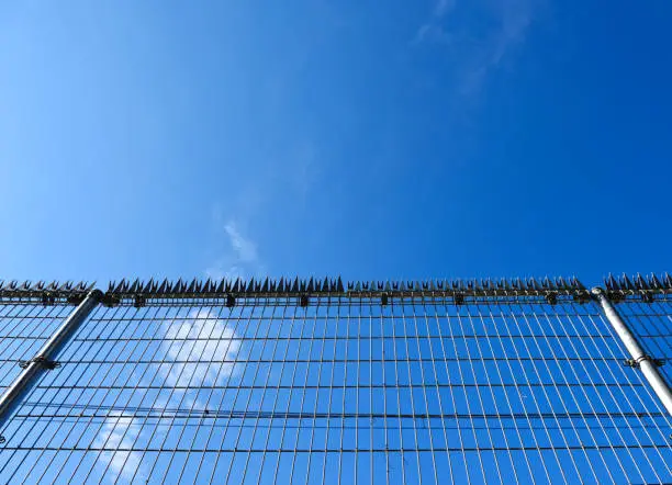 Photo of Security wire fence against blue sky