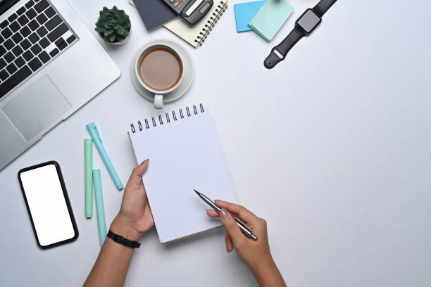 istock Above view young woman holding pen and writing on notebook. 1357813146