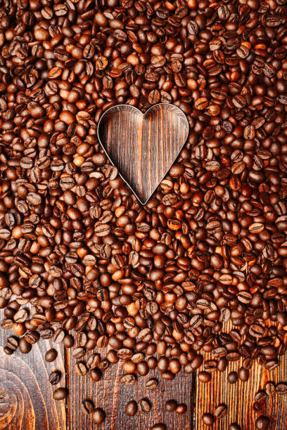 istock Background from coffee grains and a heart from coffee, the top view 1357815320