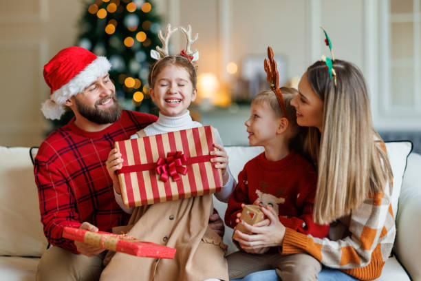 cute happy small kids siblings getting xmas gifts while sitting with young loving parents - new year people family offspring imagens e fotografias de stock