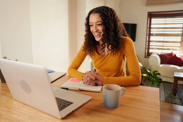 istock Multi-cultural female laughing while on online meeting. Young professional remote working with laptop in modern apartment 1357823480