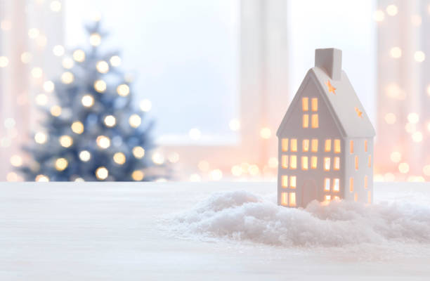 Glowing Christmas lantern of house shape on blurred holiday background stock photo