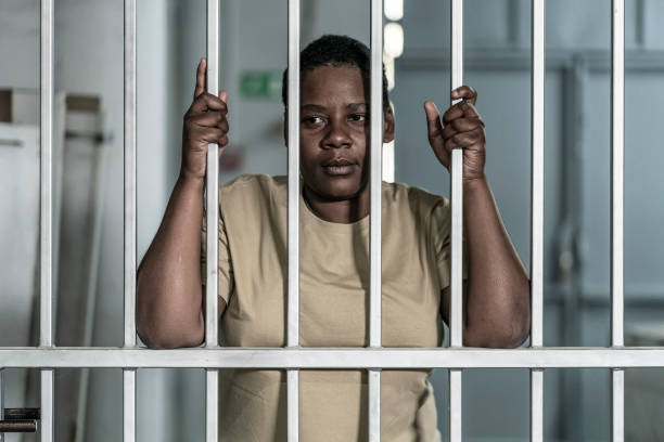 istock Young afro woman looking  serious and desperate   behind bars which may be prison bars or those of a security gate 1357823634