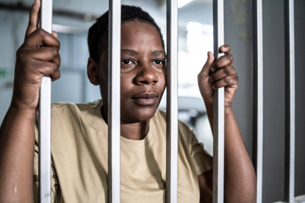 istock Young afro woman looking  serious and desperate   behind bars which may be prison bars or those of a security gate 1357823649