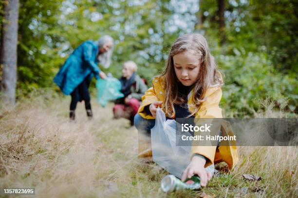 Small Girl With Mother And Grandmother Picking Up Waste Outoors In Forest Stock Photo - Download Image Now