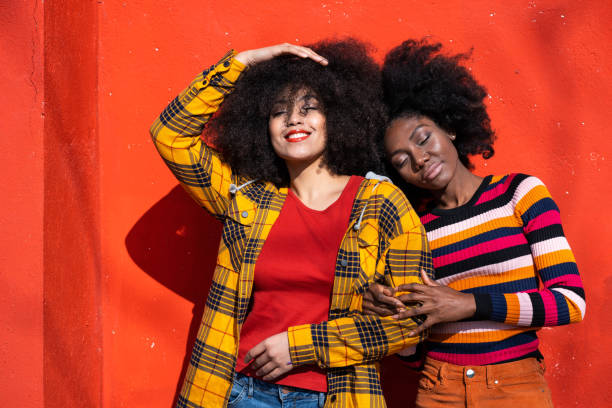 istock Cheerful afro women standing together and smiling on colorful backgraund 1357823821